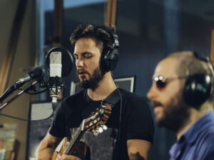 Guitarist singing in recording studio.